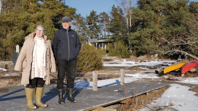Tero och Raili Tuomisto står på bryggan vid deras stuga.